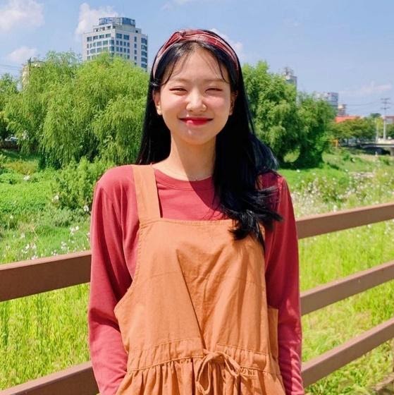 kimehwa wearing a knotted headband, a long sleeve T-shirt, and jumpsuit posing against a grassy background